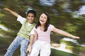 Two young children outdoors in playground spinning and smiling (blur)