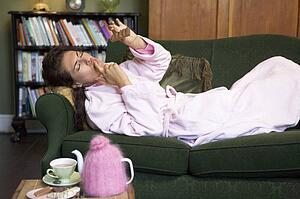 Young woman lying on sofa at home eating chocolate