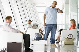 Male airline passenger waiting with other passengers in departure gate