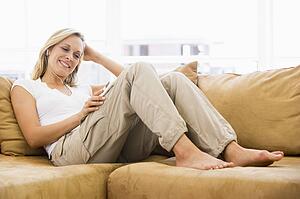 Woman in living room listening to MP3 player smiling
