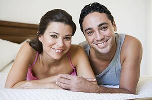 Couple relaxing on bed in bedroom smiling (selective focus)