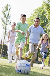 Family outdoors playing soccer and having fun