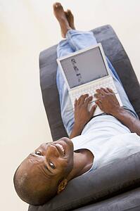 Man sitting in chair using laptop smiling