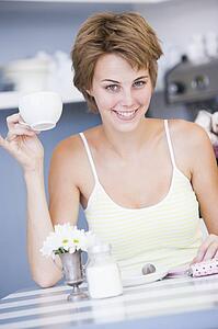 Young woman sitting at a table drinking tea