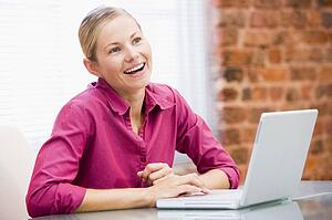 Businesswoman in office with laptop laughing