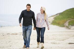 Couple walking at beach holding hands smiling