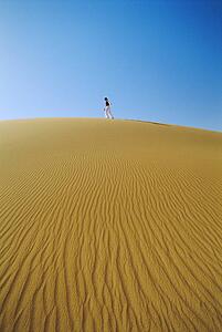 Woman outdoors walking in the desert (far away)