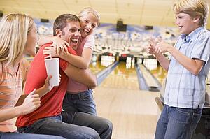 Family in bowling alley cheering and smiling