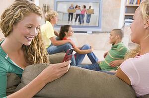Teenagers Hanging Out In Front Of Television Using Mobile Phones 