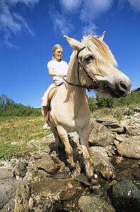 Woman outdoors riding horse through stream (fisheye)
