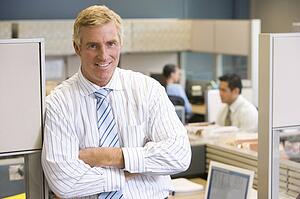 Businessman standing in cubicle smiling