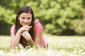 Woman lying outdoors with flower smiling