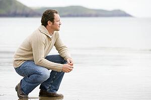 Man crouching on beach