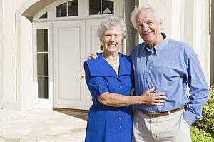 Senior couple standing outside their home