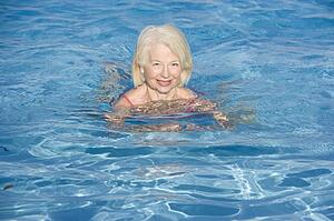 Woman swimming in outdoor pool smiling