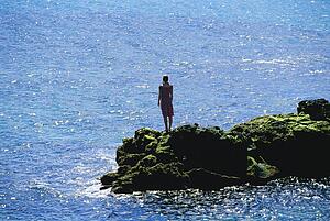 Woman outdoors standing on large rocks by the ocean