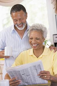 Couple relaxing with a newspaper smiling