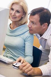 Two people at computer looking at monitor (high key)