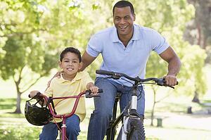 Man and young boy on bikes outdoors smiling