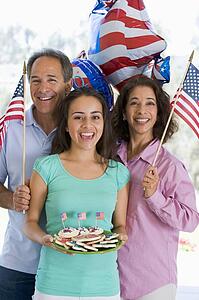 Family outdoors on fourth of July with flags and cookies smiling