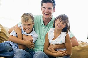 Man and two young children in living room smiling