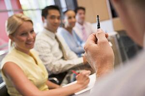 Five businesspeople at boardroom table with focus on businessman's pen