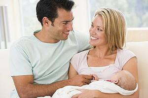 Couple in living room with baby smiling