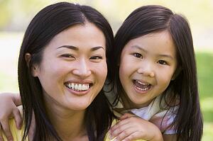 Woman and young girl outdoors embracing and smiling
