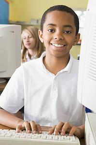 Student at computer terminal typing with student in background (selective focus)
