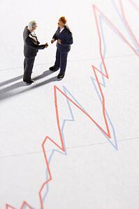 Figurines Of Two Businessmen Shaking Hands On A Line Graph