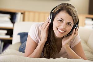 Woman in living room listening to headphones smiling