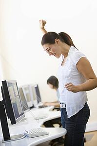 Woman standing in computer room cheering and smiling