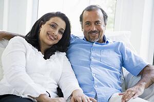 Couple sitting in living room smiling (high key)