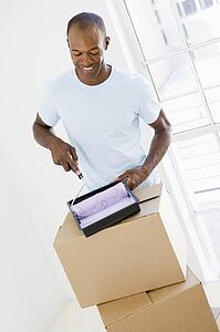 Man with roller and paint in new home smiling