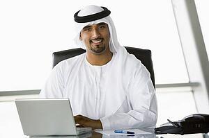 Businessman in office with laptop smiling (high key/selective focus)
