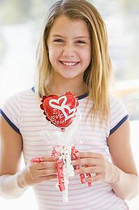 Young girl on Valentine's Day holding love themed balloon smiling