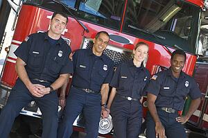 Four firefighters leaning on fire engine