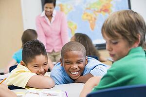 Students in class bullying student with teacher in background (selective focus)