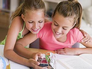 Young Girls Distracted From Their Homework, Playing With A Cellphone
