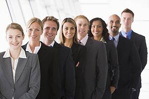 Group of co-workers standing in office space smiling (high key/depth of field)