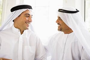 Two men sitting indoors talking and smiling (high key)