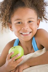 Young girl eating apple in living room smiling