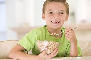 Young boy eating cereal in living room smiling