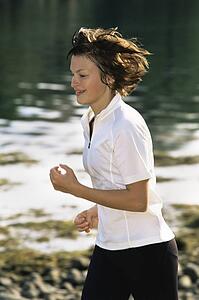 Woman outdoors by a stream running and smiling (selective focus)