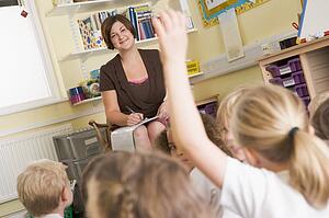 Teacher in class with student volunteering in foreground (selective focus)