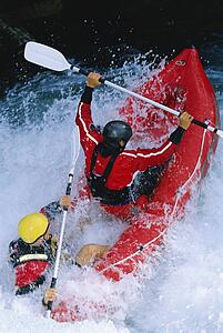 Two kayakers rowing in rapids (selective focus)