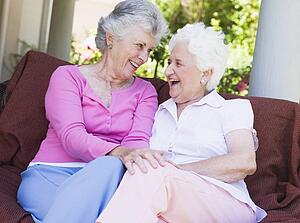 Two senior women sitting outdoors on a chair