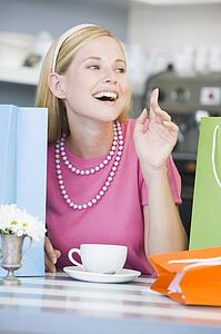 Young woman sitting at a table taking a break from shopping and drinking tea