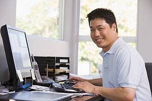 Man in home office using computer and smiling