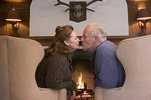 Couple sitting in living room by fireplace kissing